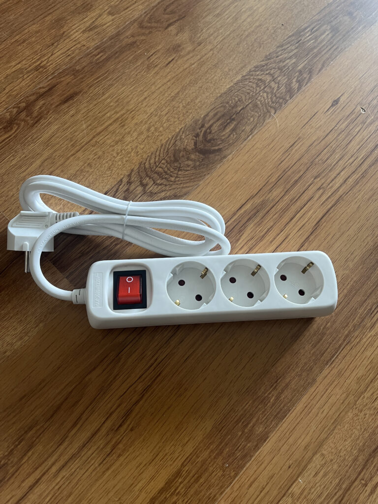 Eine 3-fach Steckdosenleiste mit einem An- und Ausschalter. Das Kabel ist aufgewickelt und nicht eingesteckt.